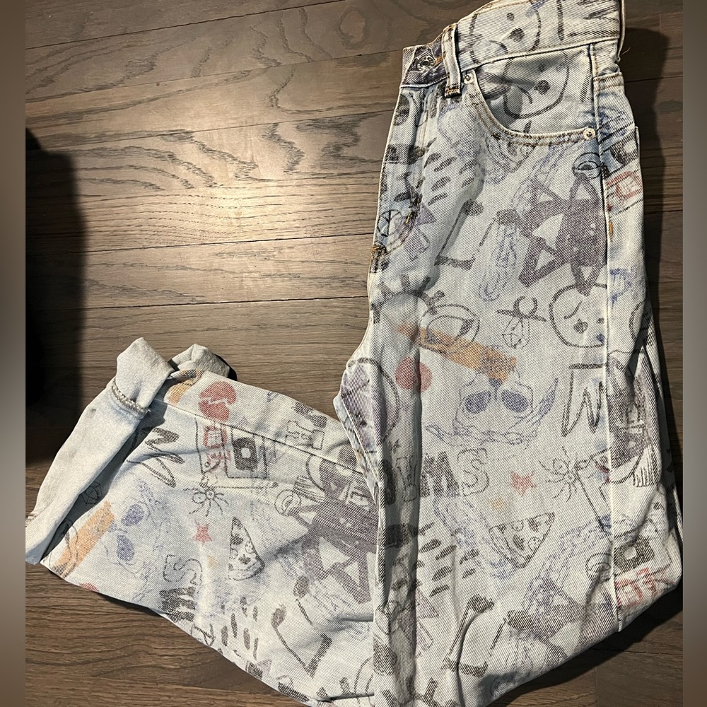 Light wash boyfriend style jean with graffiti details and folded ankle bottom.